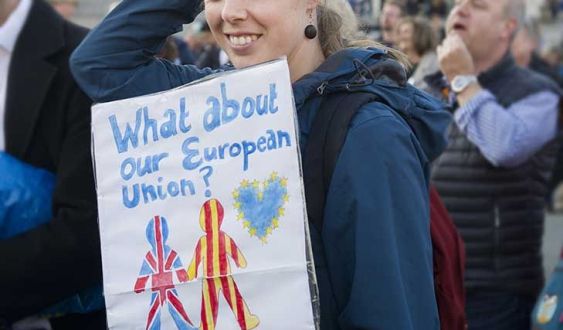 A woman is pictured while holding a banner writting on it '