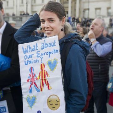 A woman is pictured while holding a banner writting on it '