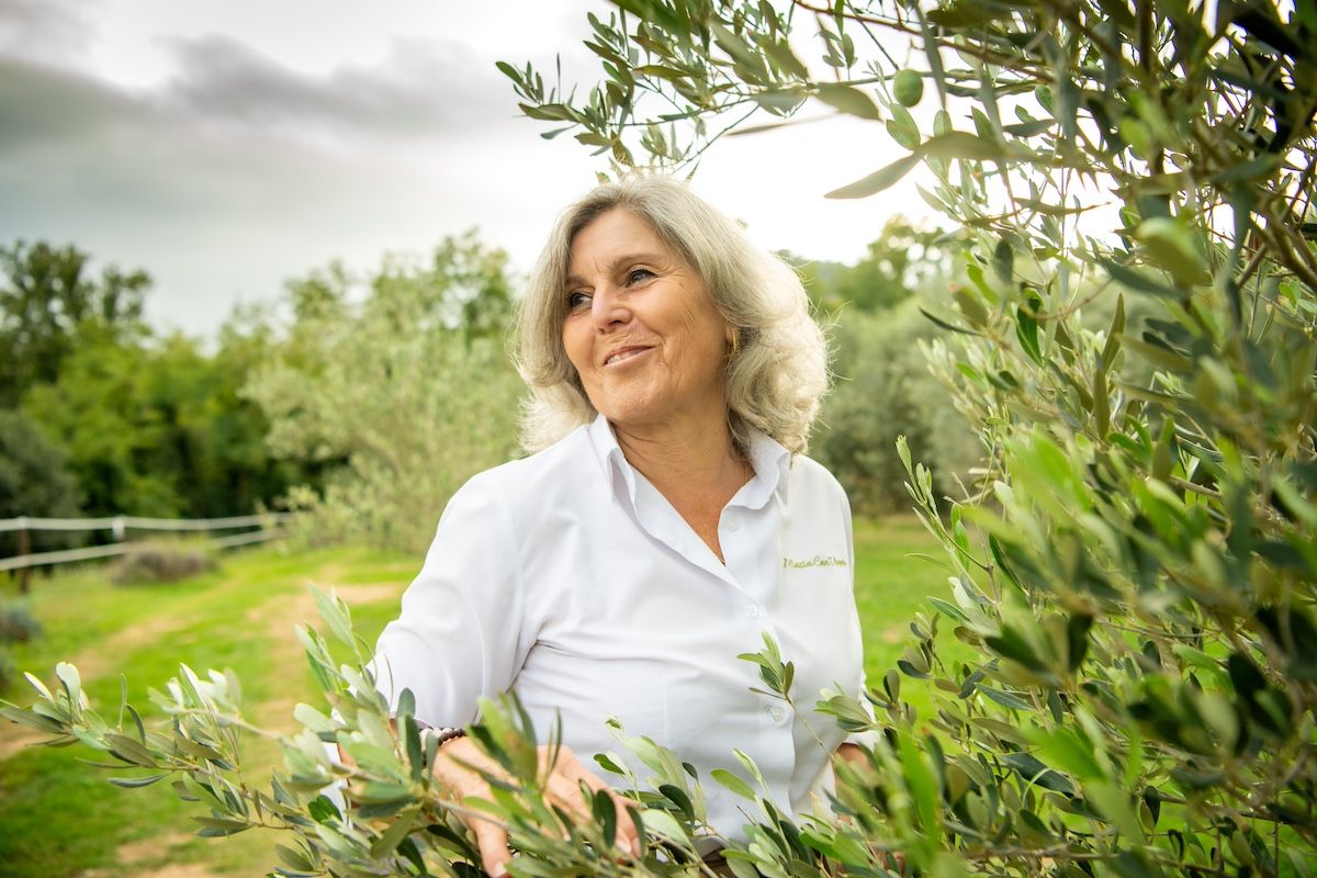 Rosa Mª Pérez passejant entre les oliveres de varietat vera que han contribuït a recuperar, per Sergio Ros
