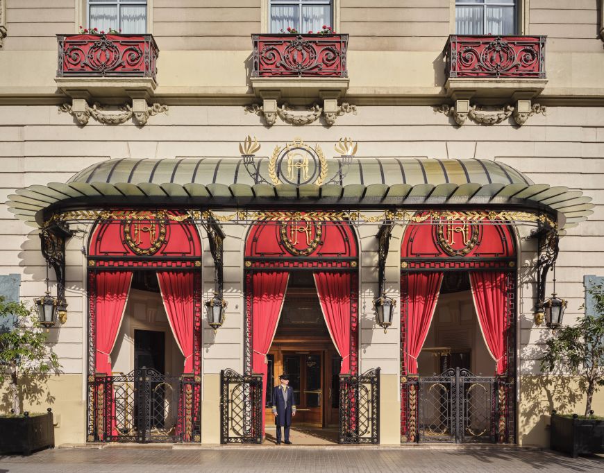 El acceso principal al hotel Palace en primavera de 2026. El rojo predomina en el chaflán de Gran Via con Roger de Llúria. © Royal Blue Bird