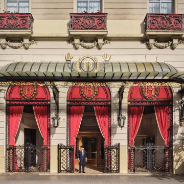 The main entrance to the Palace Hotel in spring 2026. Red dominates the chamfered corner at Gran Via and Roger de Llúria. © Royal Blue Bird