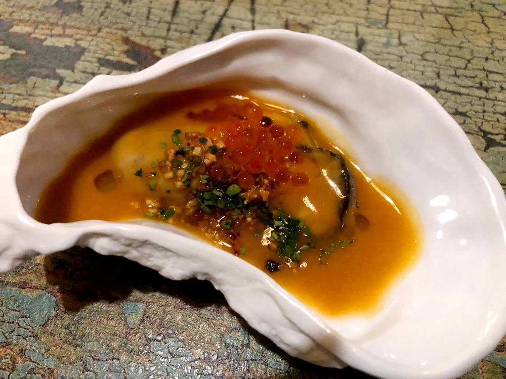 Ostra en suquet de pescado de roca con picada catalana y huevas de truchas.