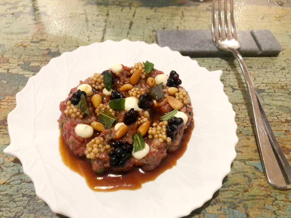 Tartar de solomillo de vaca con jugo reducido infusionado con hierbas aromáticas, moras, piñones tostados, semillas de mostaza encurtidas y mayonesa de raifort.