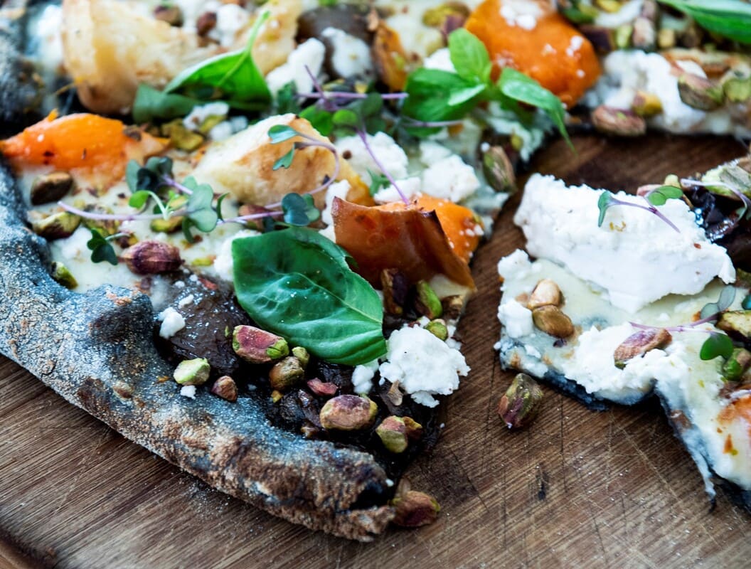Pizza negra de calabaza, celeri, cebolla caramelizada, pistachos y queso de cabra ecológico de The Green Spot. ©The Green Spot